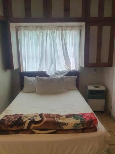 a bedroom with a bed with a window at Valleycenter guestlodge in Johannesburg