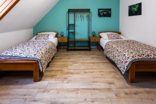 two beds in a room with blue walls and wooden floors at Mitter-ház Panzió in Zalaszentgrót