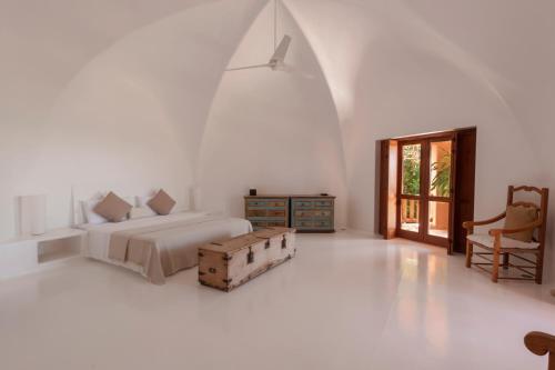 a white bedroom with a bed and a chair at Villa La Ceiba in La Huerta