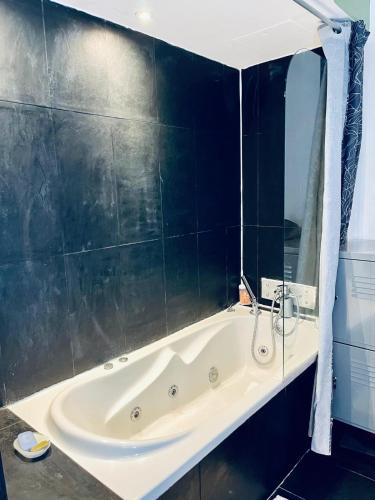 a bath tub in a bathroom with black tiles at Nice - Stylish apartment downtown in Nice