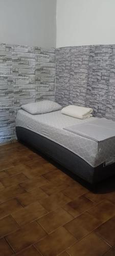 a bed in a room with a brick wall at pousada popular in Barreiras