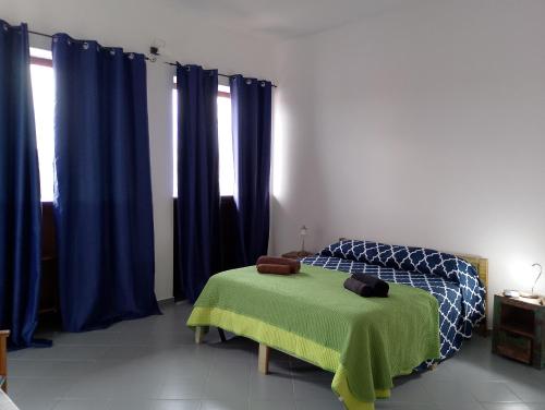 a bedroom with blue curtains and a bed with a green blanket at SU MARINERI in Càbras