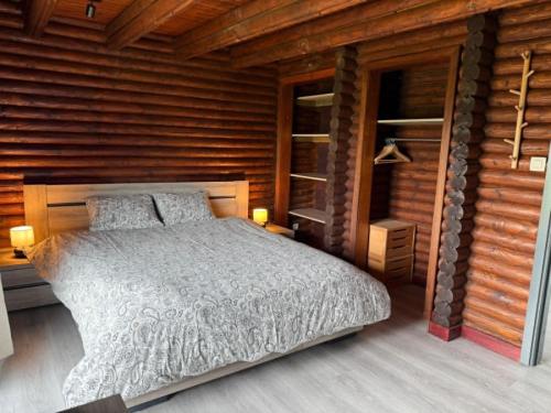 a bedroom with a bed in a wooden cabin at Le Caroline du Nord in Tenneville
