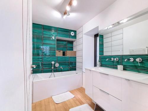 a bathroom with a tub and a green wall at Le Moulin Hochet in Les Pieux