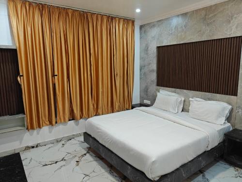 a bedroom with a large bed with an orange curtain at The Ooty Suites in Ooty