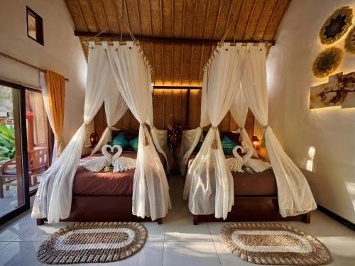 two beds in a room with white drapes at Meket Bungalows in Nusa Penida