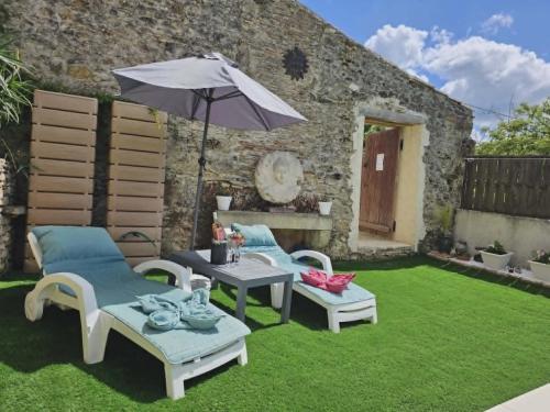 a patio with a table and chairs and an umbrella at Love Room "Les Secrets de Winna" in Augé