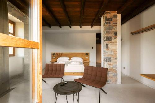 a bedroom with a bed and two chairs and a table at Cascina Belvedì in Clanezzo