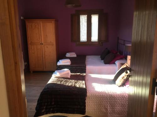 three beds in a room with purple walls at La Masia del Batlle in Sarroqueta