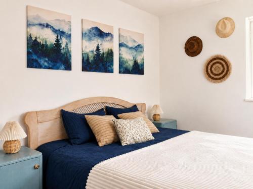 a bedroom with a bed and four paintings on the wall at Blue Cottage in Şpring