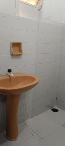 a bathroom with a brown sink and white tiled walls at pousada popular in Barreiras