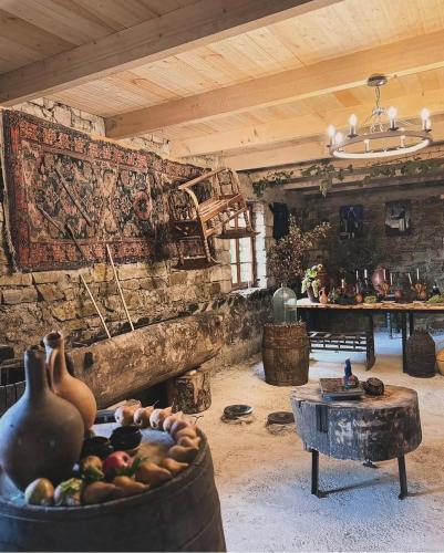 a room with a stone wall with a table and a pot of fruit at Uplistsikhis saamo in Kʼvakhvreli