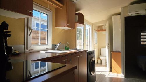 a kitchen with a sink and a washing machine at Bungalow entre oliviers et pins, -10mn de la plage in Châteauneuf-lès-Martigues