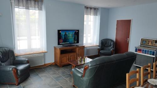 a living room with a couch and a television at Le Balcon de la Pierre Claire in Villersexel