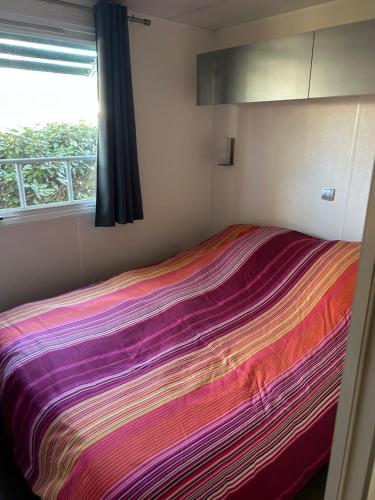a bed in a room with a colorful blanket at Mobil-home Messanges in Messanges