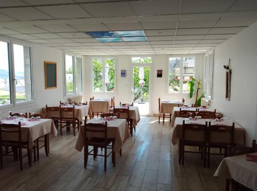 a dining room with tables and chairs and windows at Le café de la place in Saint-Germain-du-Teil