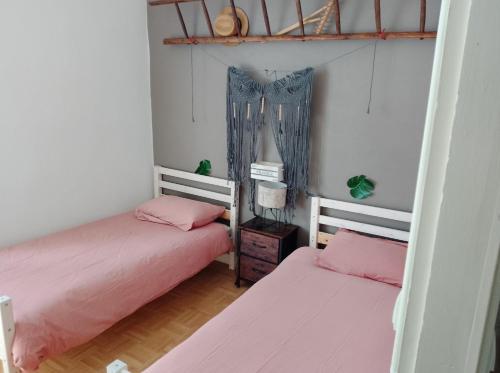 two beds in a room with pink sheets at Le café de la place in Saint-Germain-du-Teil