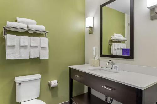 a bathroom with a sink and a mirror and a toilet at Sleep Inn & Suites Liberty in Liberty