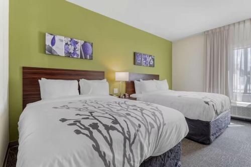 two beds in a hotel room with green walls at Sleep Inn & Suites Liberty in Liberty