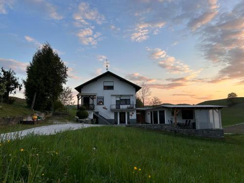a white house with a grass field in front of it at Apartma in Wellness Sladka Gora in Šmarje pri Jelšah