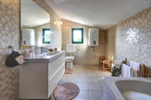 a bathroom with a tub and a sink and a toilet at Villa Stone Pearl with heated swimming pool in Sveti Filip i Jakov