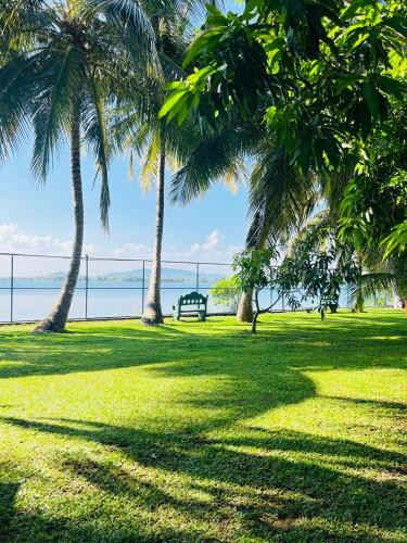 a park with palm trees and a bench in the grass at Yala Elephant Cottage in Tissamaharama