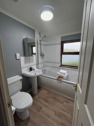 a bathroom with a white toilet and a sink at Woodside Lodge, Weybourne, Holt in Weybourne