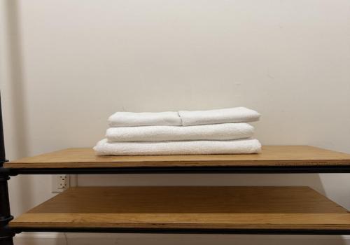 a stack of white towels on a wooden shelf at Chelsea Rooms NYC in New York