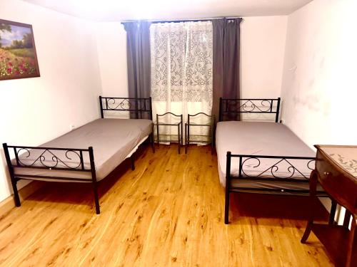 two beds in a room with wooden floors and a window at Haus Ksena in Wirmsthal