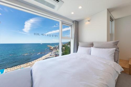a bedroom with a large white bed and a large window at Donghae 828 Spa Pension A in Donghae