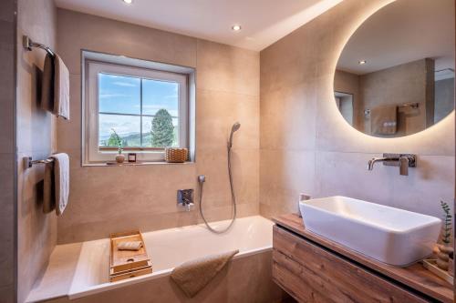 a bathroom with a sink and a tub and a mirror at Appartement Felsenheim in Westendorf
