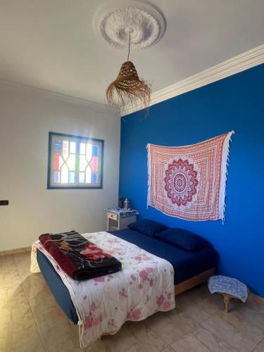 a blue bedroom with a bed and a window at Villa Rabia in Sidi Kaouki