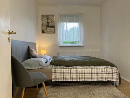 a bed in a room with a chair and a window at FBC Roms Business in Rødby