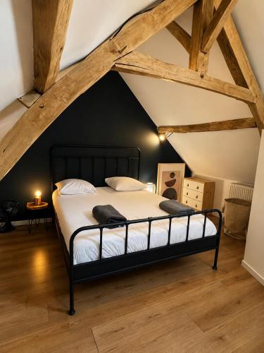 a bedroom with a black bed in a attic at Le nid de Bertille in Le Vaudreuil