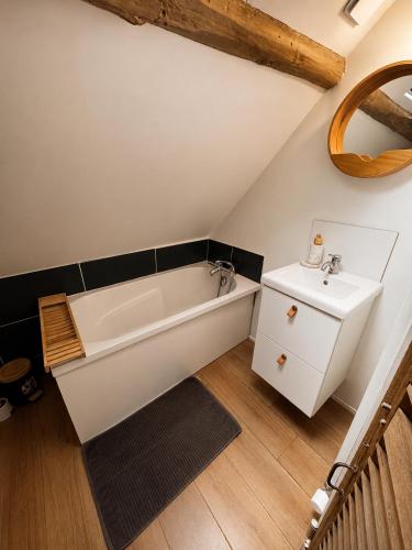 a bathroom with a white bath tub and a sink at Le nid de Bertille in Le Vaudreuil