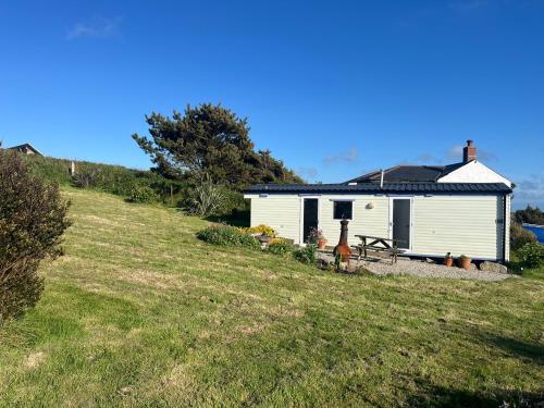 a white house on the side of a grassy hill at Carn Kenidjack View Caravan, space, peace and tranquillity in Penzance