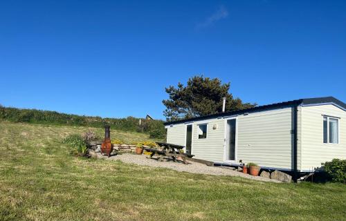 a small white shed with a picnic table in front of it at Carn Kenidjack View Caravan, space, peace and tranquillity in Penzance