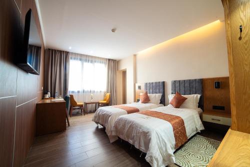 ein Hotelzimmer mit zwei Betten und einem Fernseher in der Unterkunft Barkat hôtel in Baraki