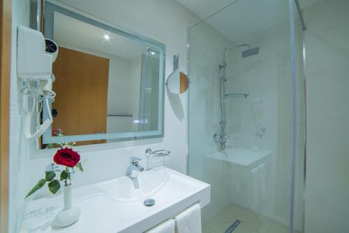 ein weißes Badezimmer mit Waschbecken und Dusche in der Unterkunft Barkat hôtel in Baraki