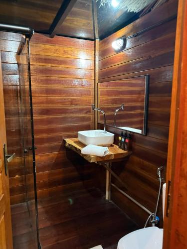 a bathroom with wooden walls and a sink and a toilet at AREIA BRANCA Chalés in Santo Amaro