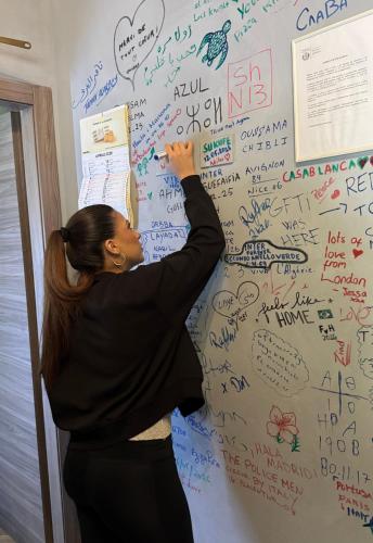 a woman standing in front of a wall with writing on it at Gloria Hostel Milano in Milan