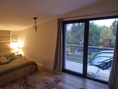 a bedroom with a large sliding glass door with a balcony at Paradise Vibe Balaton in Balatonkenese