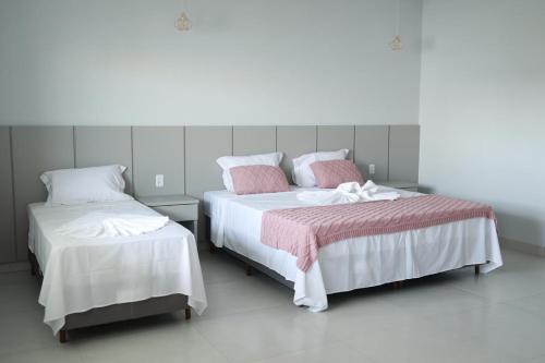 a bedroom with two beds with pink and white sheets at Pousada Villa Ricca Park in Niquelândia