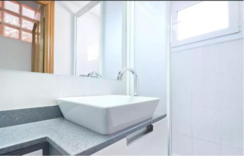 a white bathroom with a sink and a mirror at Sea Apartament in Sant Adria de Besos