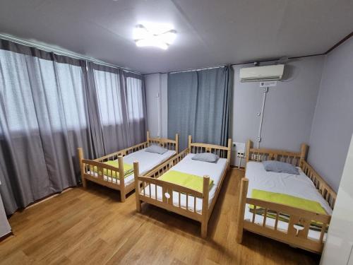 a room with three beds and a window at Welcome Busan Guesthouse in Busan