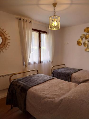 a bedroom with two beds and a chandelier at Palmiers 1 in Barbotan-les-Thermes