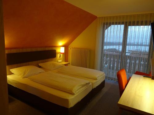 ヴェルトハイムにあるGasthof Hotel Zum Rossのベッドと大きな窓が備わるホテルルームです。