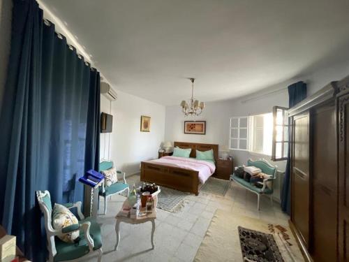 a bedroom with a bed and chairs in a room at Villa Jasmin in Hammamet