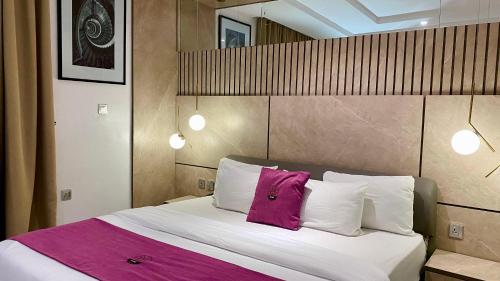 a bedroom with a large bed with a pink pillow at Purple Lavender Hotel Lekki in Lekki