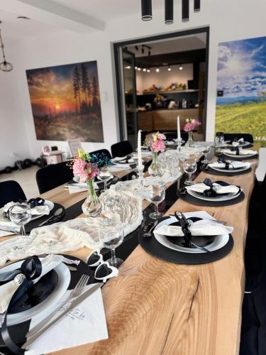 a long wooden table with plates and wine glasses at Domki u Duszy Wielka Dusza in Brenna